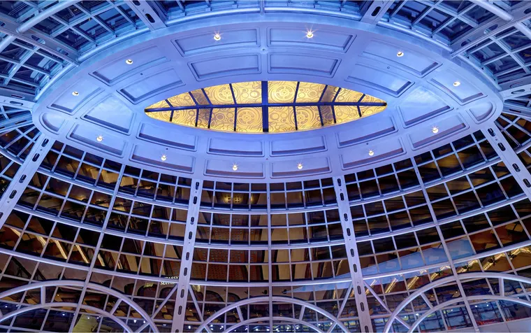 Fallsview Casino Resort at night: its glass rotunda over the rear concourse, lit blue, seen from below.